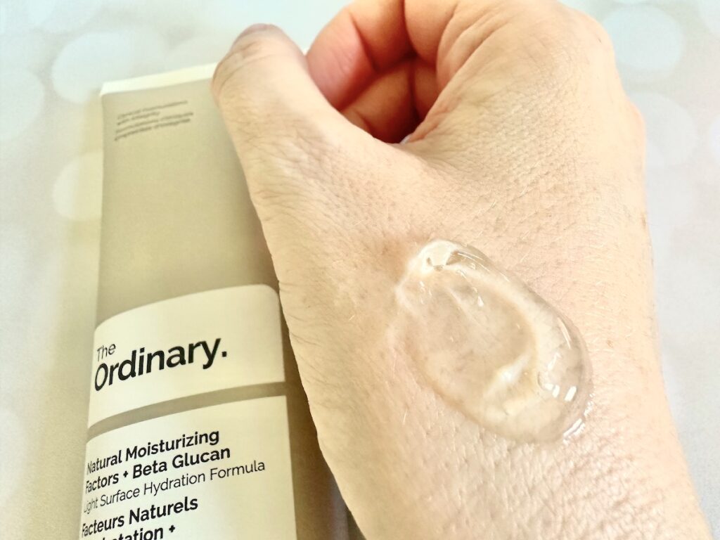 The Ordinary Natural Moisturizing Factors + Beta-Glucan, flatlay of tube next to sample on hand.