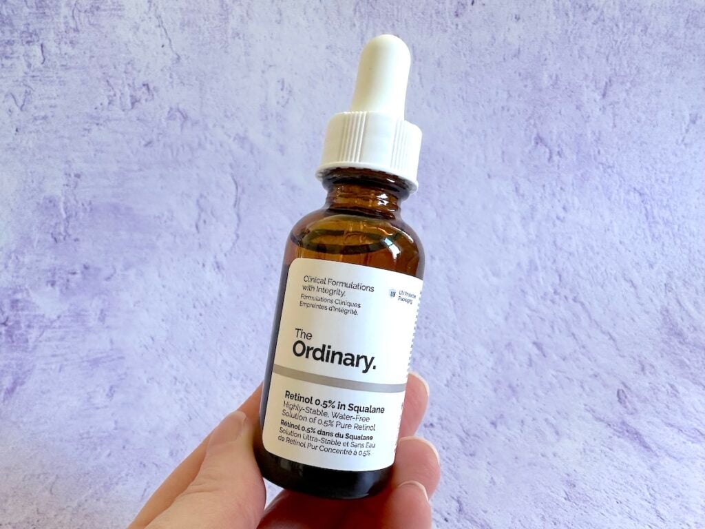 The Ordinary Retinol 0.5% In Squalane, handheld in front of purple background.