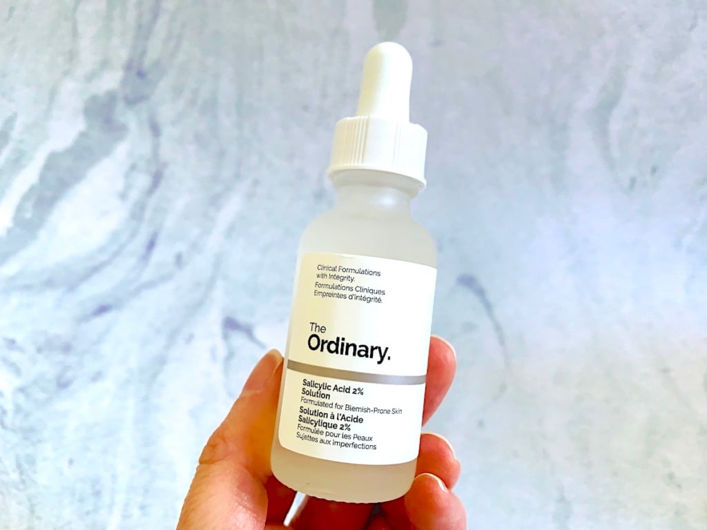 The Ordinary Salicylic Acid 2% Solution (Reformulated) handheld on blue background