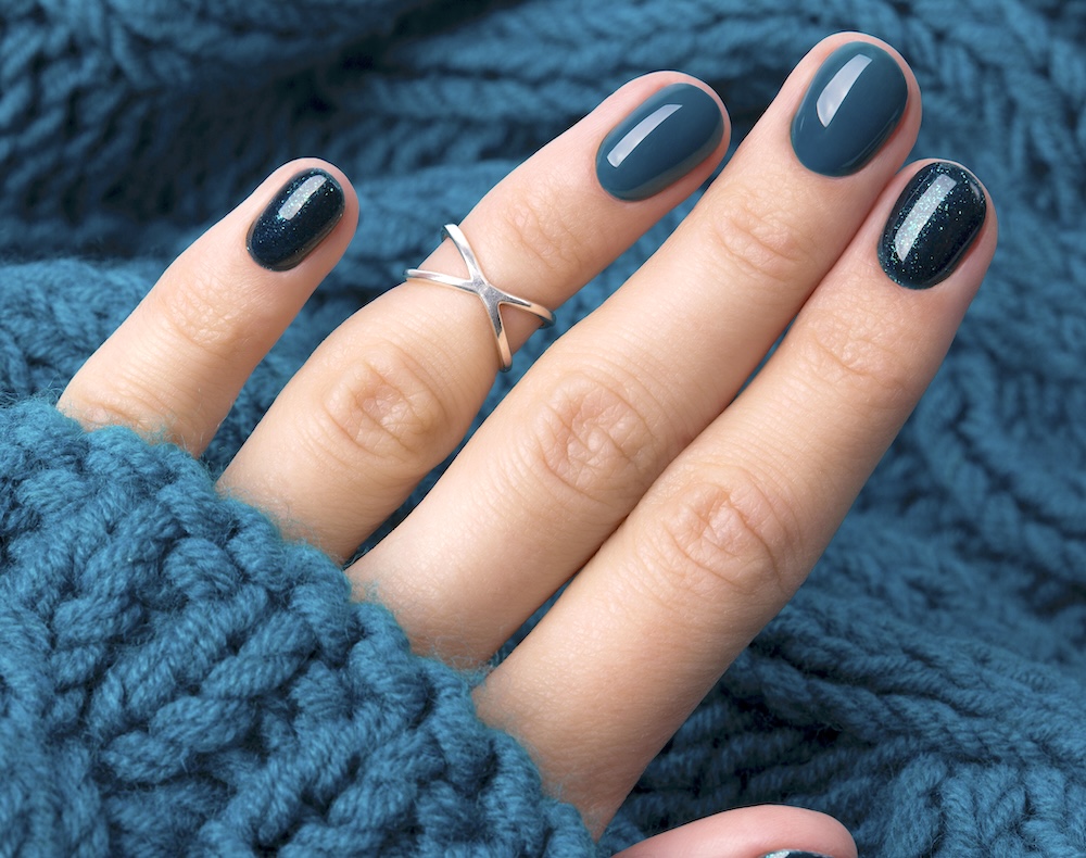 Teal blue winter nails surrounded by teal sweater.