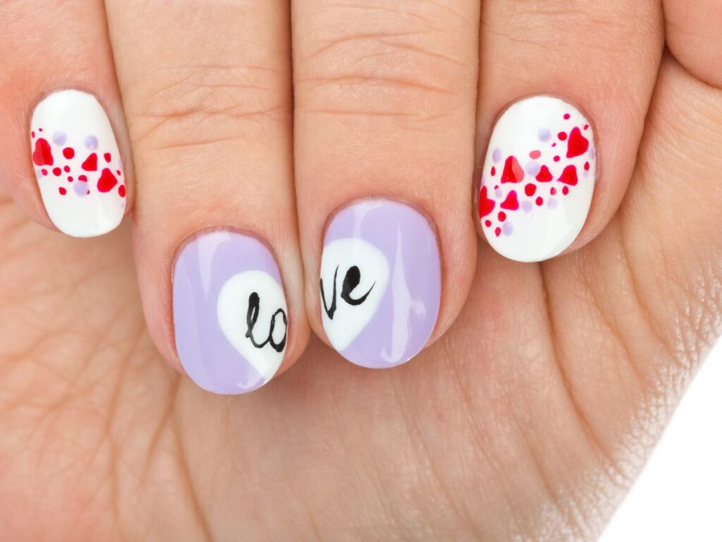 Red hearts and purple "love" on white Valentines day nails.