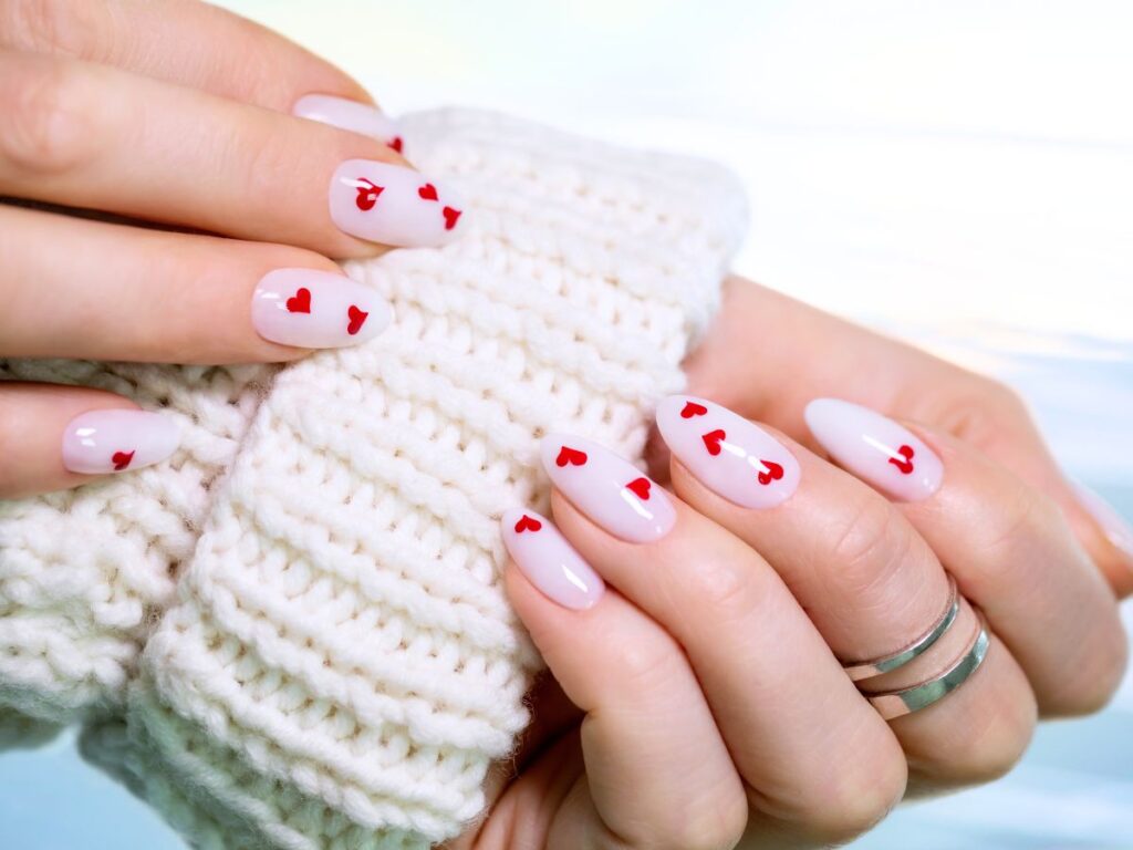 Milky white almond anils with a sprinkle of red hearts and cream knit sweater sleeve.