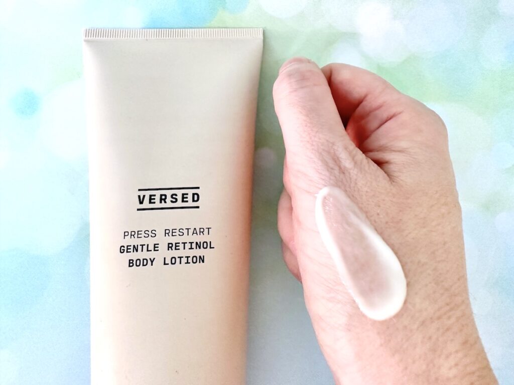 Versed Press Restart Gentle Retinol Body Lotion, flatlay next to sample on hand.