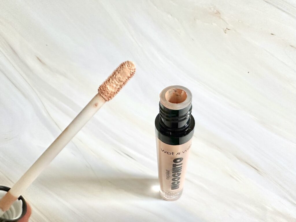 Wet n’ Wild Megalast Incognito Concealer in the shade Light Beige, open tube with applicator wand.