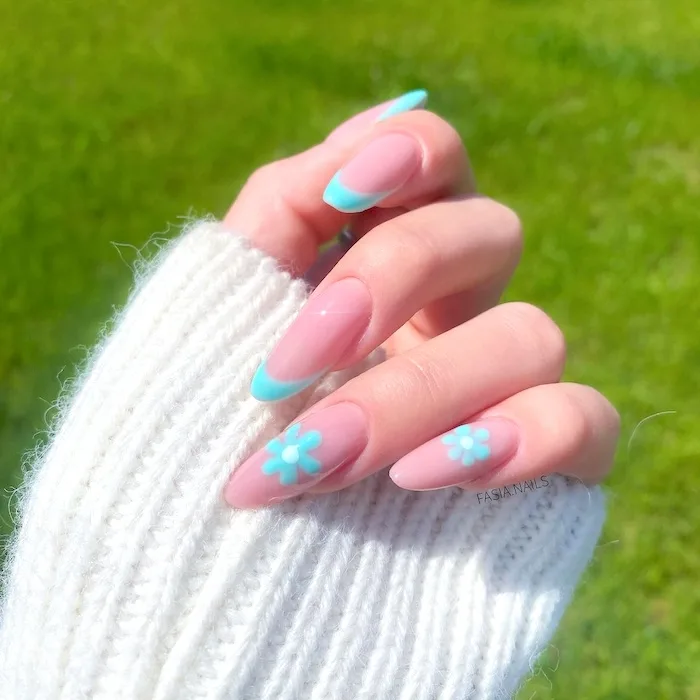 Aqua blue flower April nails in front of grass background.