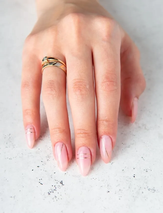 Pink minimalist nails with thin gold lines.