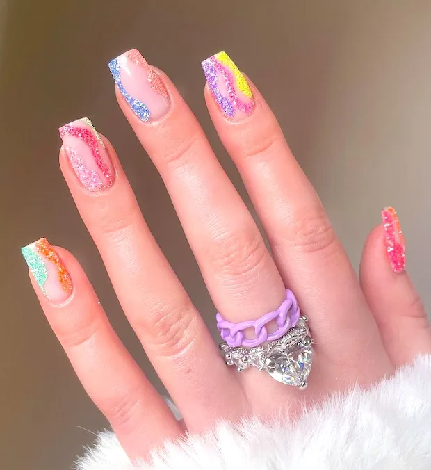 Glitter April nails with colorful swirls.