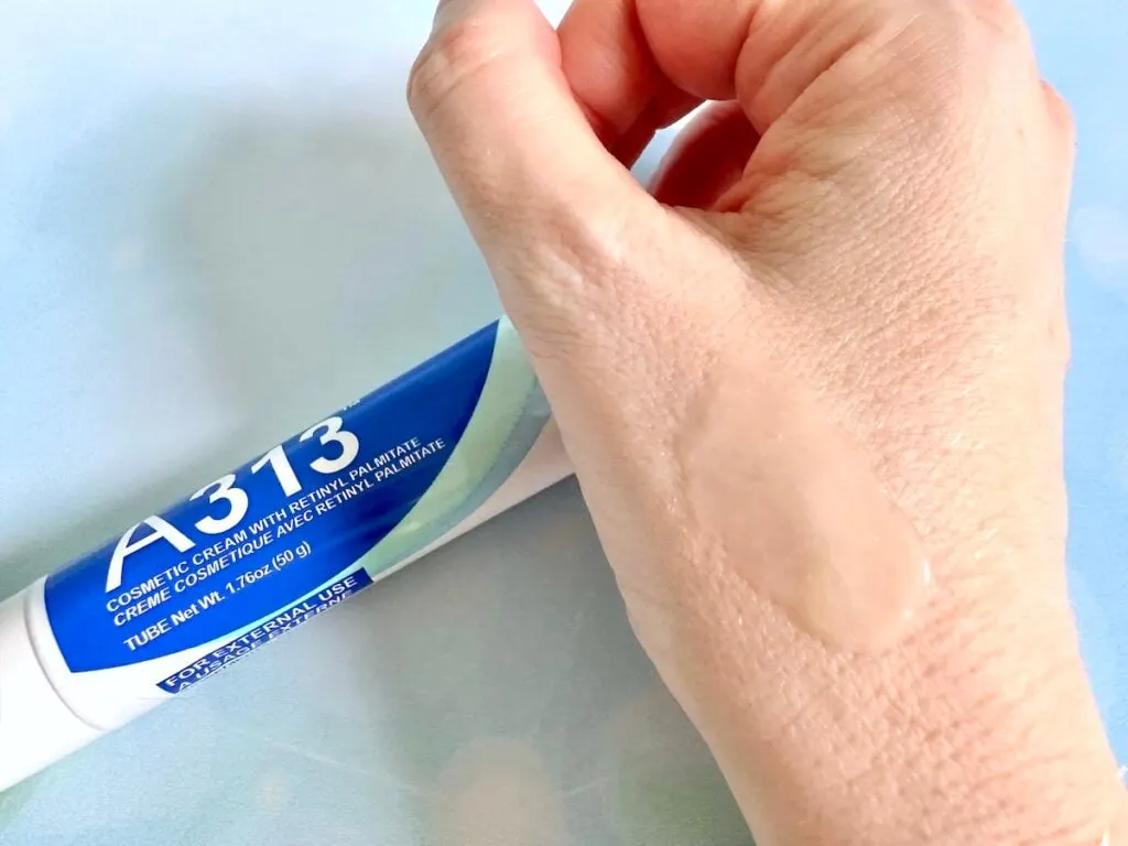 A313 Cosmetic Cream With Retinyl Palmitate, flatlay of tube next to sample on hand.