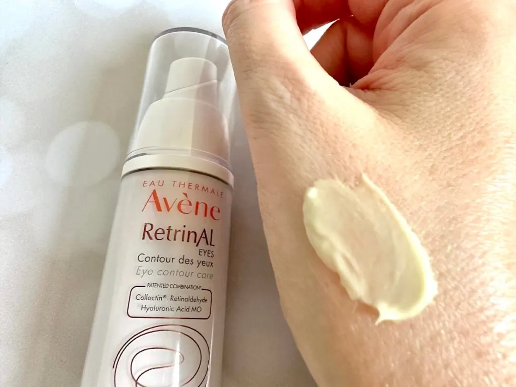 Avene RetrinAL Eyes Eye Cream flatlay next to sample on hand.