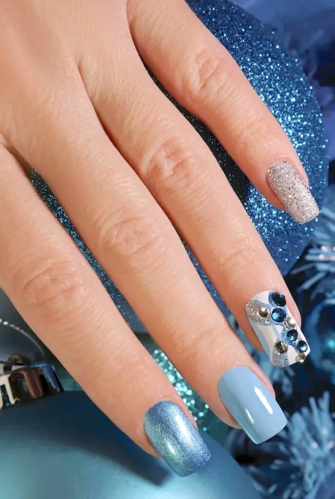 Sparkly blue winter nails design with rhinestones.