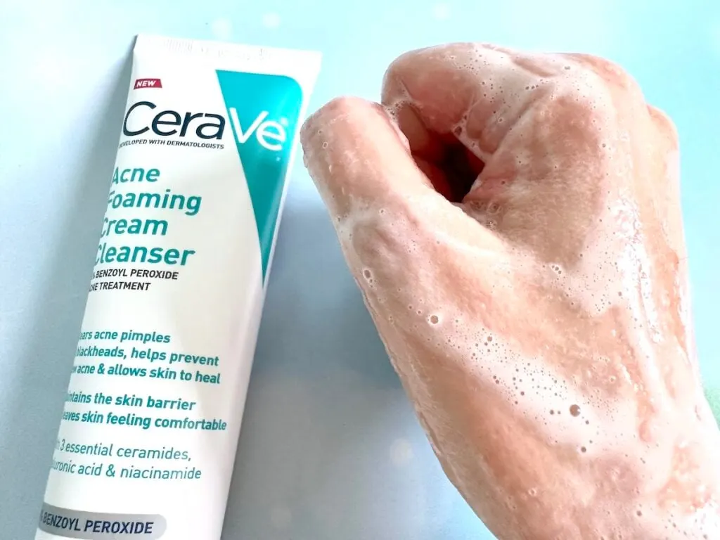 CeraVe Acne Foaming Cream Cleanser, flatlay of tube next to foam sample on hand.