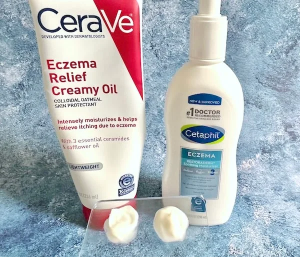 CeraVe Eczema Relief Creamy Oil and Cetaphil Eczema Restoraderm Soothing Moisturizer bottles, next to samples on clear spatula.