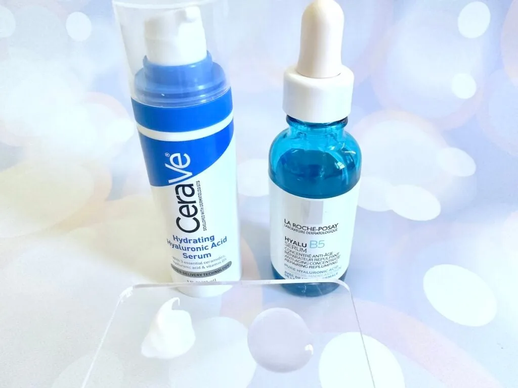 CeraVe Hyaluronic Acid Serum vs La Roche-Posay Hyalu B5 Pure Hyaluronic Acid Serum, bottles next to samples on clear cosmetic spatula.