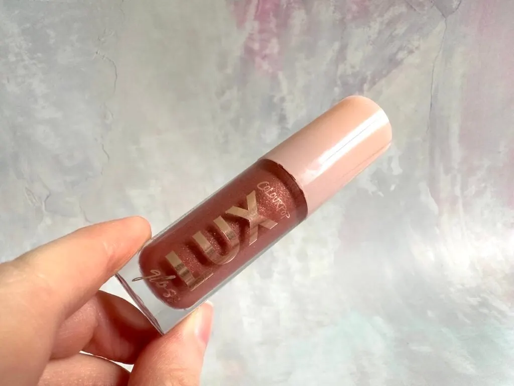 ColourPop Lux Lip Gloss in the shade Com Thru, handheld.