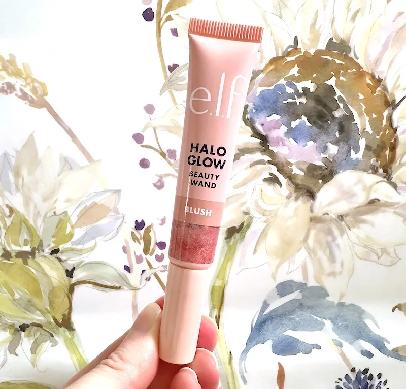 E.l.f. Halo Glow Blush Beauty Wand in the shade Rose You Slay, handheld on floral background.