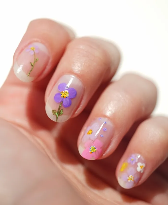 Pressed flowers nail art on natural nail background.