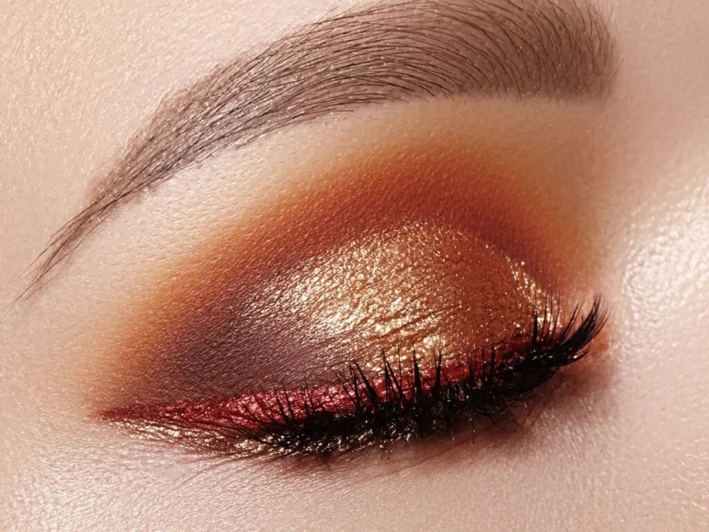 Brone and gold glitter eye makeup look on a closed eye.