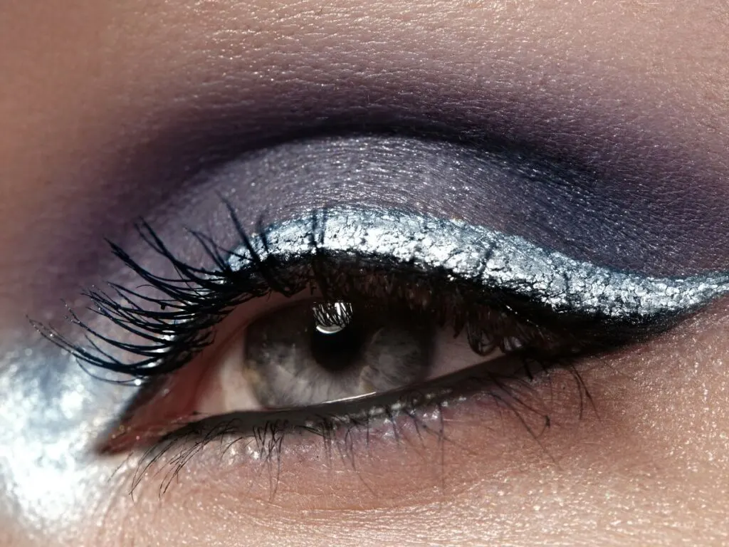 Bright light silver glitter on the eyelash line and deep purple gray eyeshadow on the eyelids.