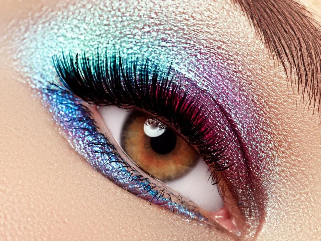 Multi-color eyeshadow look of pastel glittery eyeshadow. Brown eye angled downward.