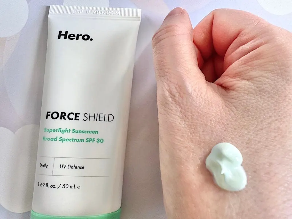 Hero Cosmetics Force Shield Superlight Sunscreen Broad Spectrum SPF 30 flatlay, next to sample on hand.