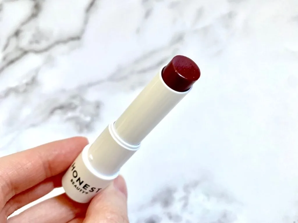 Honest Beauty Tinted Lip Balm in the shade Plum Drop handheld.