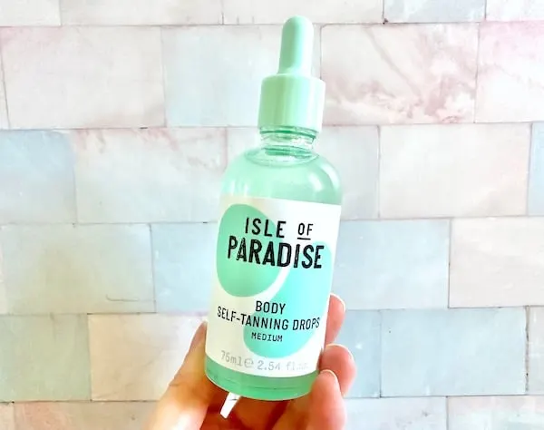 Isle of Paradise Self-Tanning Firming Body Drops in the shade Medium, handheld.