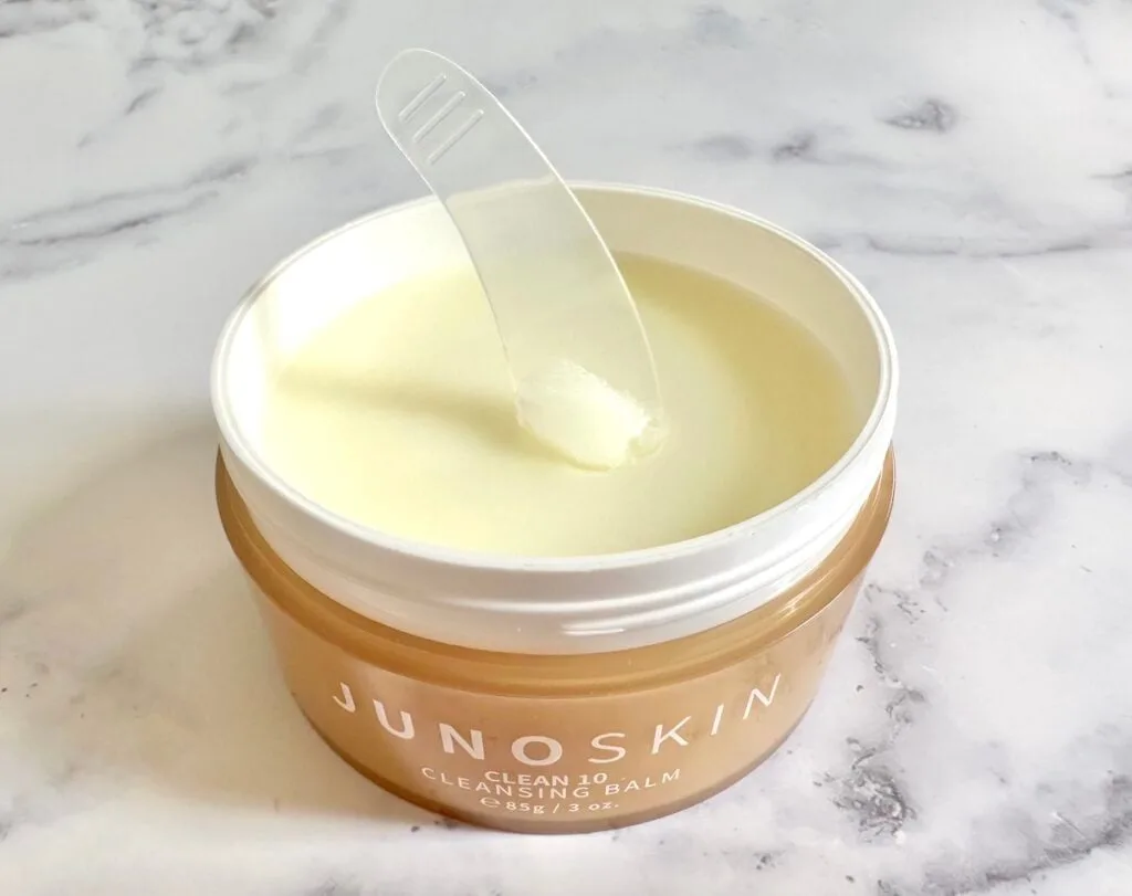 Juno & Co. Clean 10 Cleansing Balm, open jar with clear cosmetic spatula.