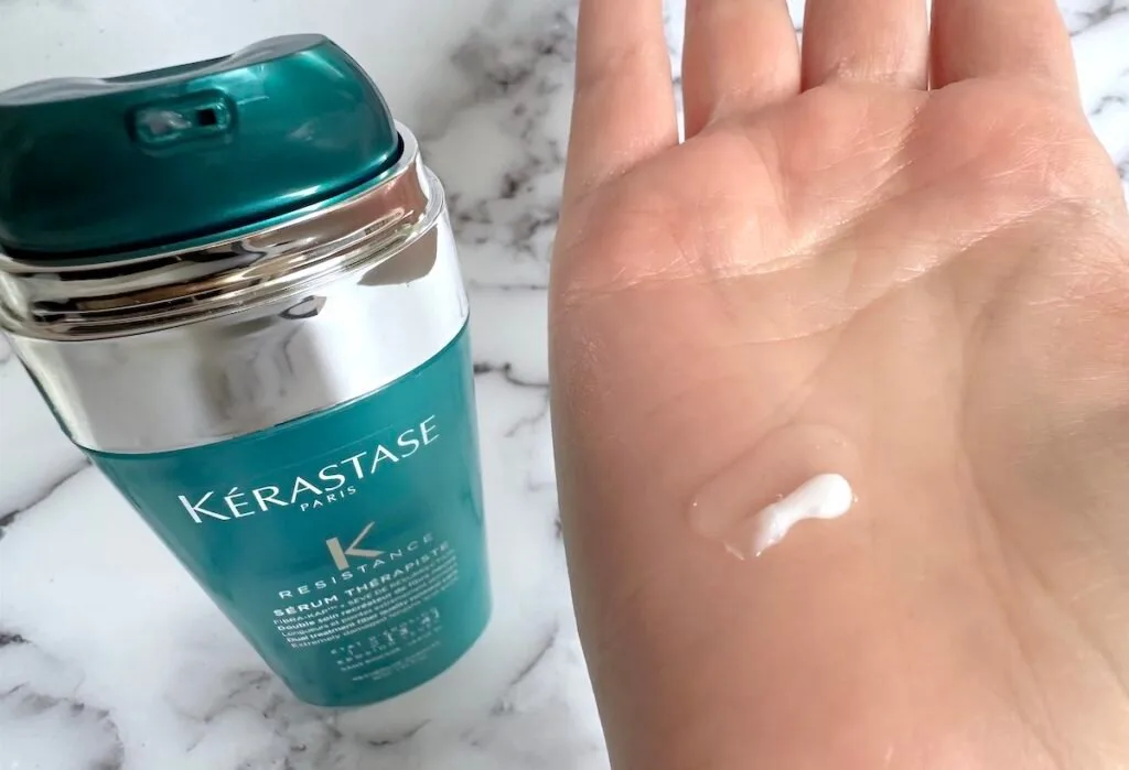 Kerastase Resistance Sérum Thérapiste Hair Serum bottle next to sample on palm of hand.