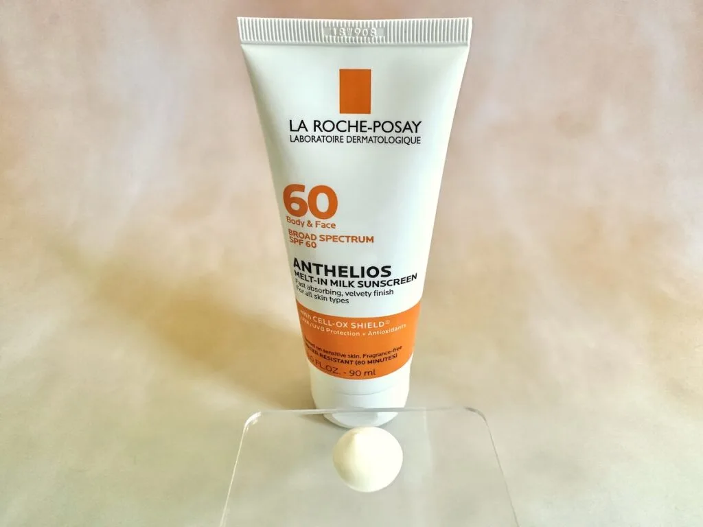 La Roche-Posay Anthelios Melt-In Milk Sunscreen SPF 60, tube behind sunscreen sample on clear plastic spatula.