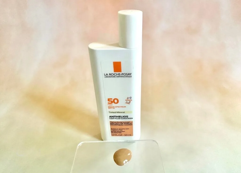 La Roche-Posay Anthelios Mineral Tinted Sunscreen SPF 50, bottle behind sunscreen sample on clear plastic spatula.