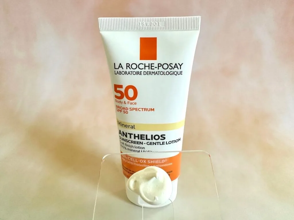 La Roche-Posay Anthelios SPF 50 Gentle Lotion Mineral Sunscreen, tube behind sunscreen sample on clear plastic spatula.