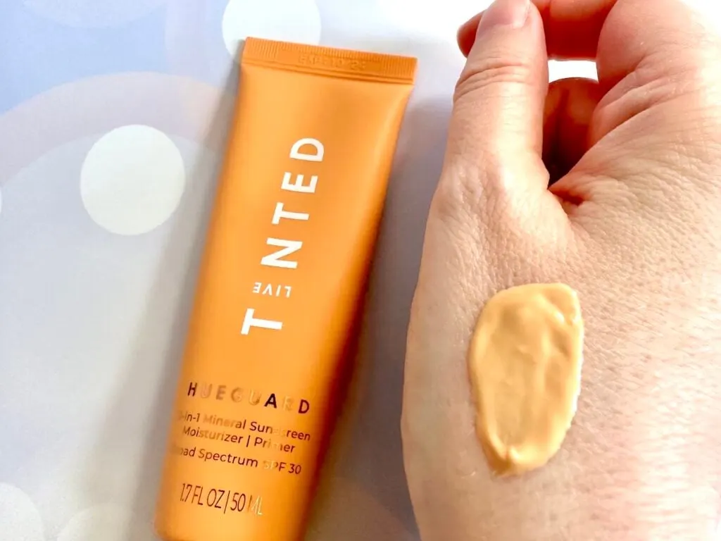 Live Tinted Hueguard 3-in-1 Mineral SPF 30 Moisturizer Primer flatlay, next to sample on hand.