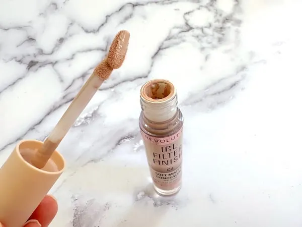 Makeup Revolution IRL Filter Finish Concealer in the shade C4: open bottle of concealer with flat tip contour wand applicator, handheld.