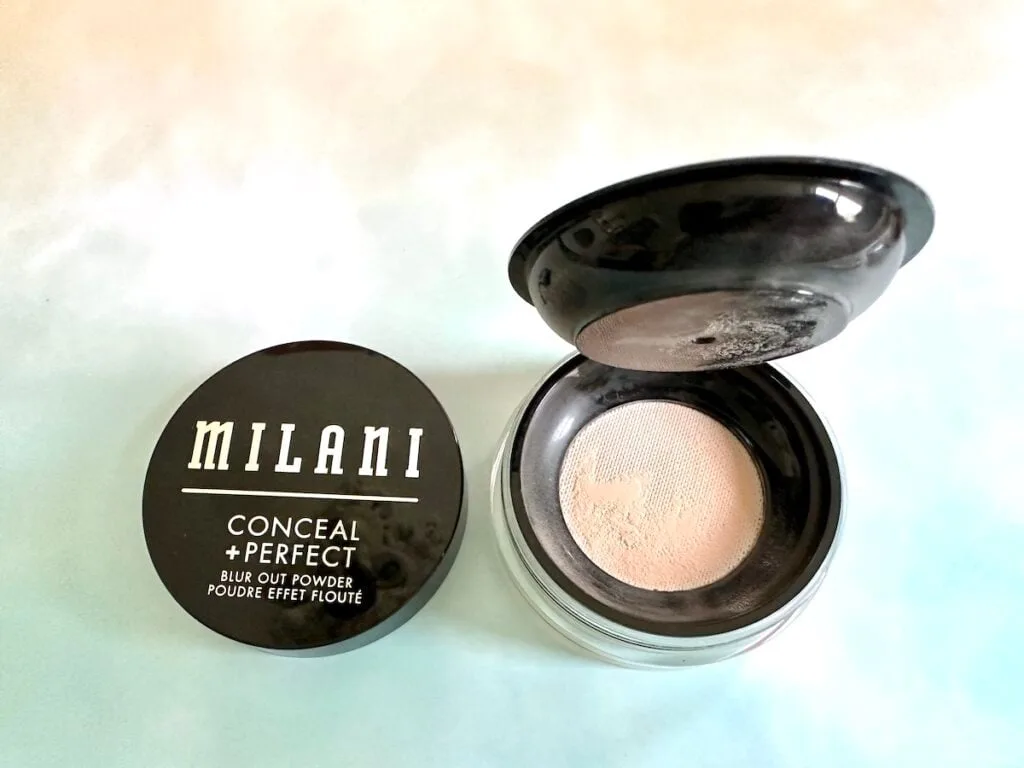 Milani Conceal + Perfect Blur Out Powder in the shade Translucent, open jar with lid and interior cap open.