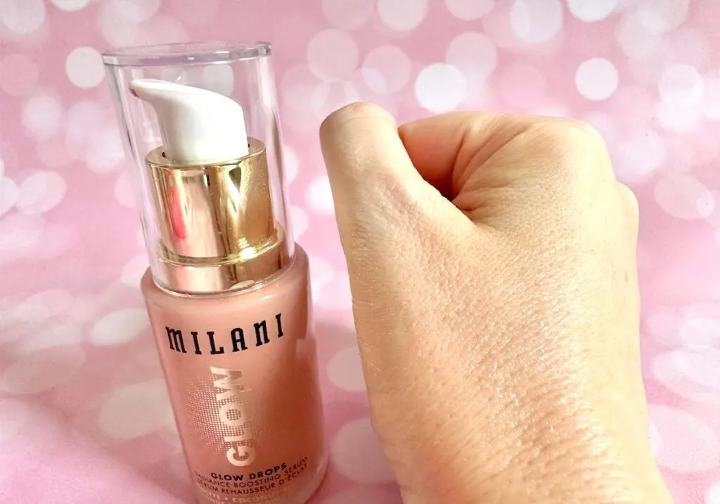 Milani Glow Drops Radiance Boosting Serum, bottle next to sample absorbed on hand.