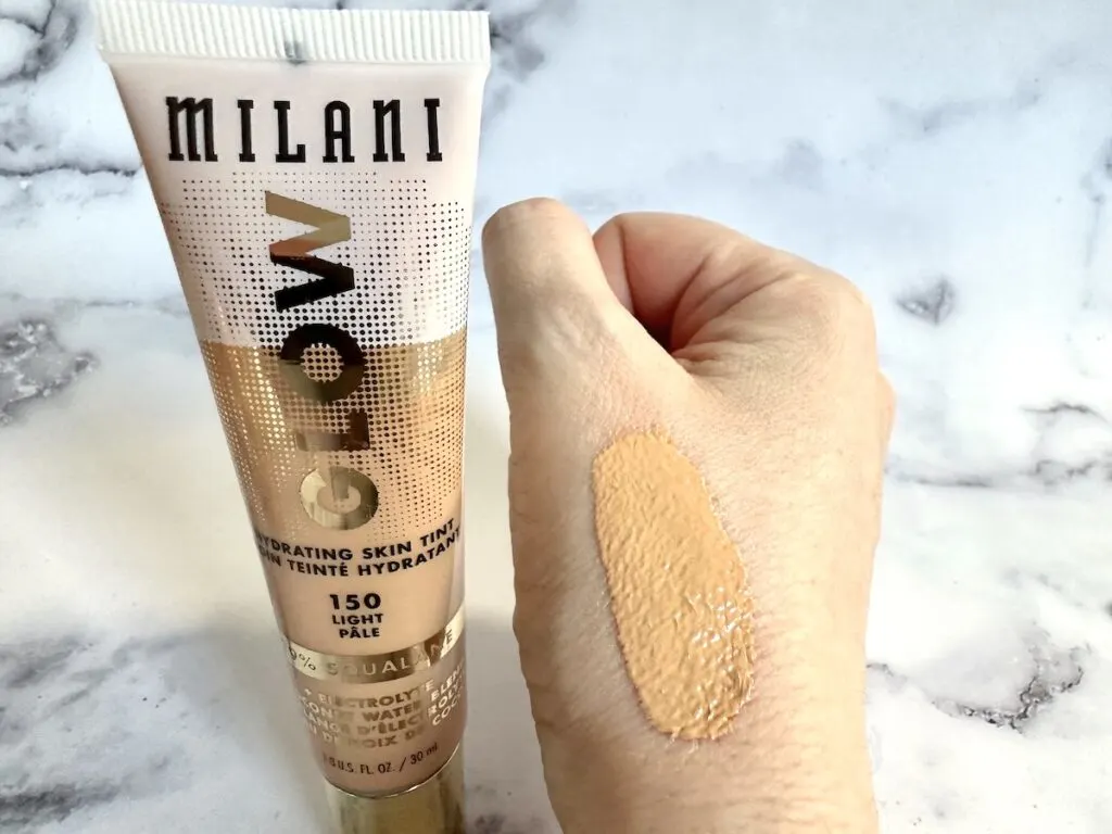 Milani Glow Hydrating Skin Tint tube next to sample on hand.