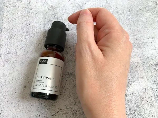 NIOD Survival 0 Antioxidant Serum bottle and rubbed into hand