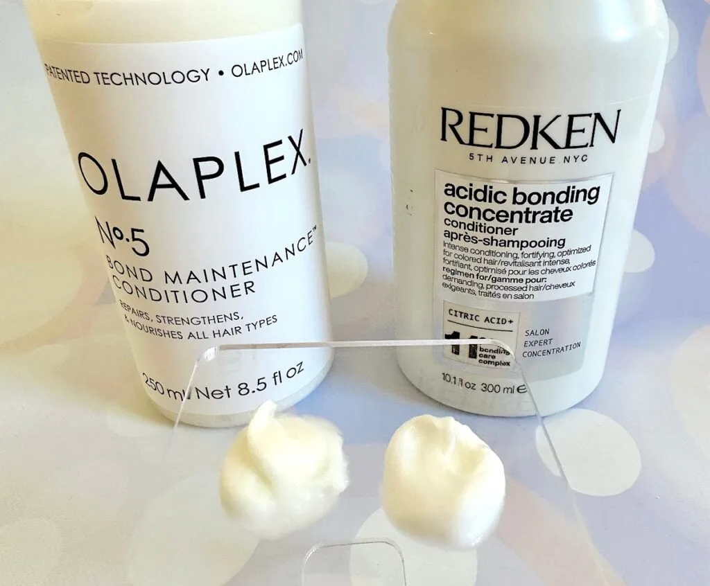 Olaplex No. 5 Bond Maintenance Conditioner and Redken Acidic Bonding Concentrate Conditioner bottles behind samples on clear plastic spatula.