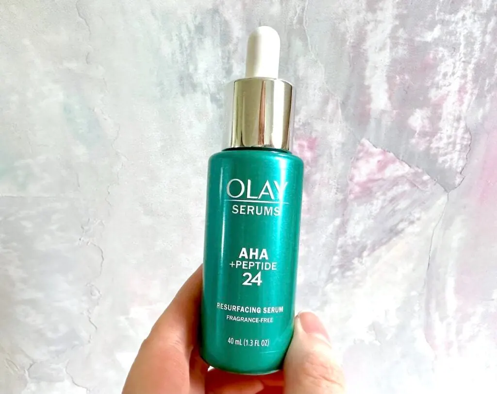 Olay AHA + Peptide 24 Serum, handheld.