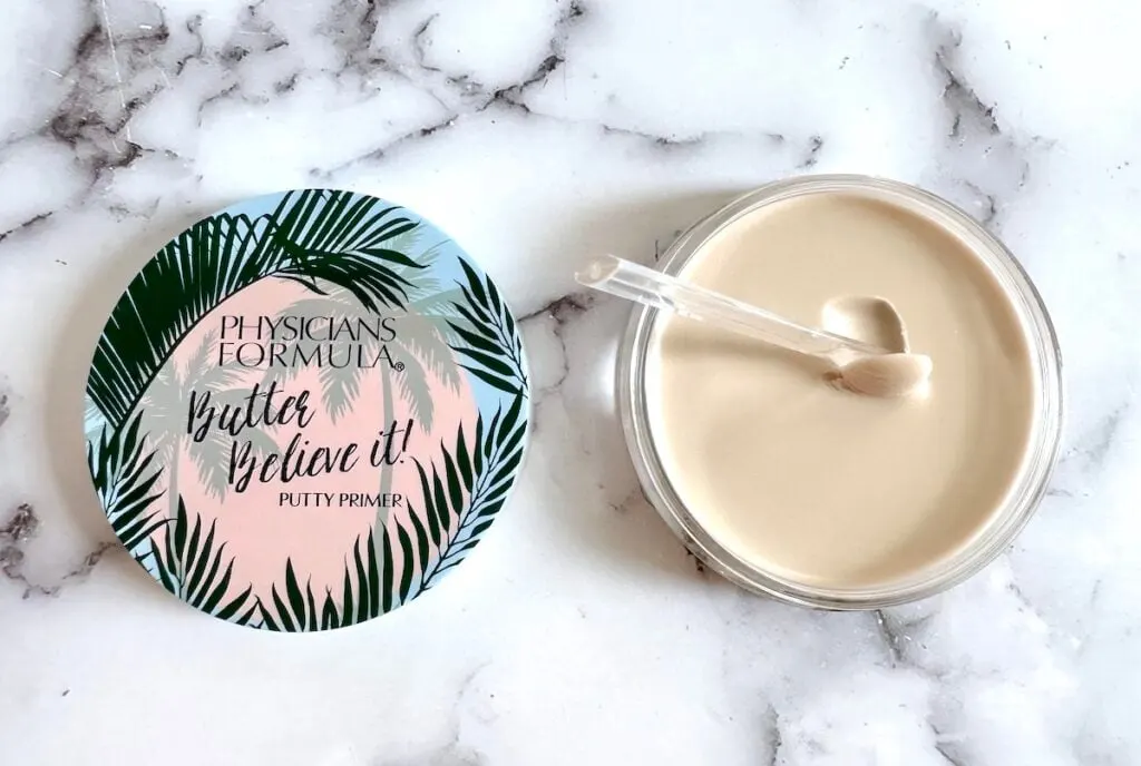 Physicians Formula Butter Believe It! Putty Primer, open jar with clear cosmetic spatula, flatlay.