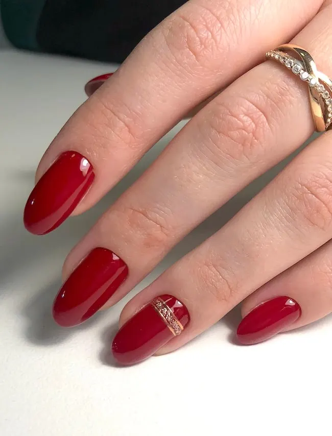 Red almond nails with glittery gold line.