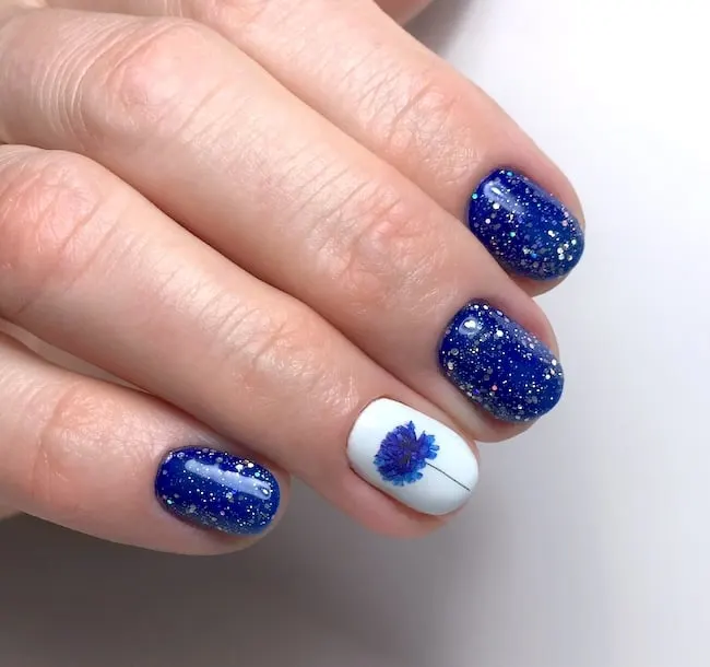 Short blue glitter flower nails.