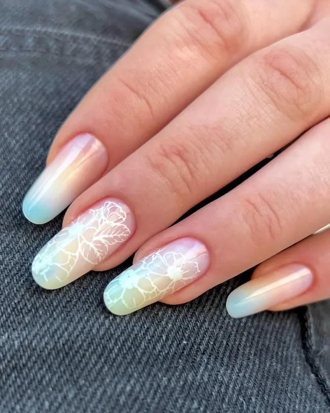 Pastel floral nails on dark denim background.