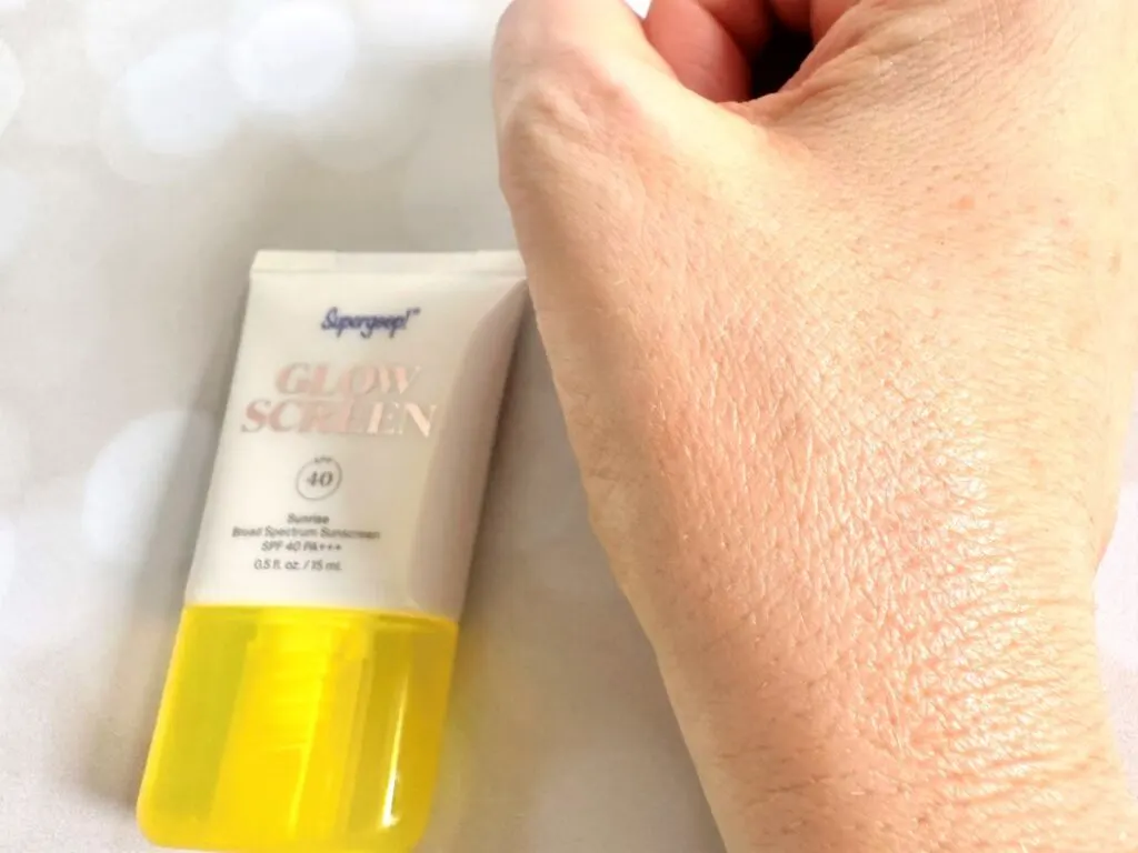 Supergoop! Glowscreen Sunscreen SPF 40, flatlay of tube next to sample absorbed on hand.