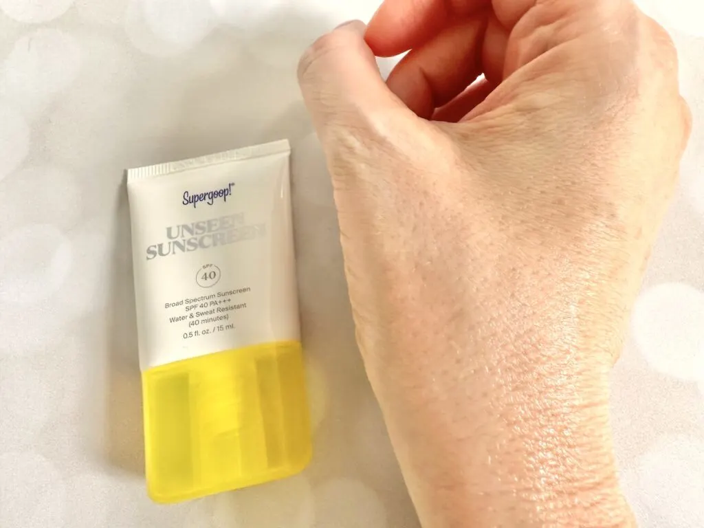 Supergoop! Unseen Sunscreen SPF 40, flatlay of tube next to sample on hand, absorbed.