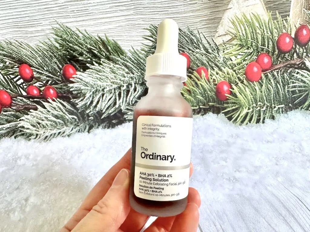 The Ordinary AHA 30% + BHA 2% Peeling Solution, handheld in front of Christmas holly.