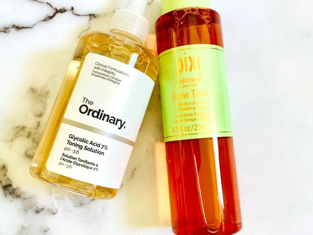 The Ordinary Glycolic Acid 7% Toning Solution and Pixi Glow Tonic flatlay on a white marble background.