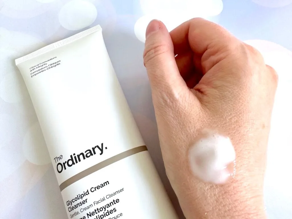 The Ordinary Glycolipid Cream Cleanser flatlay next to sample on hand.