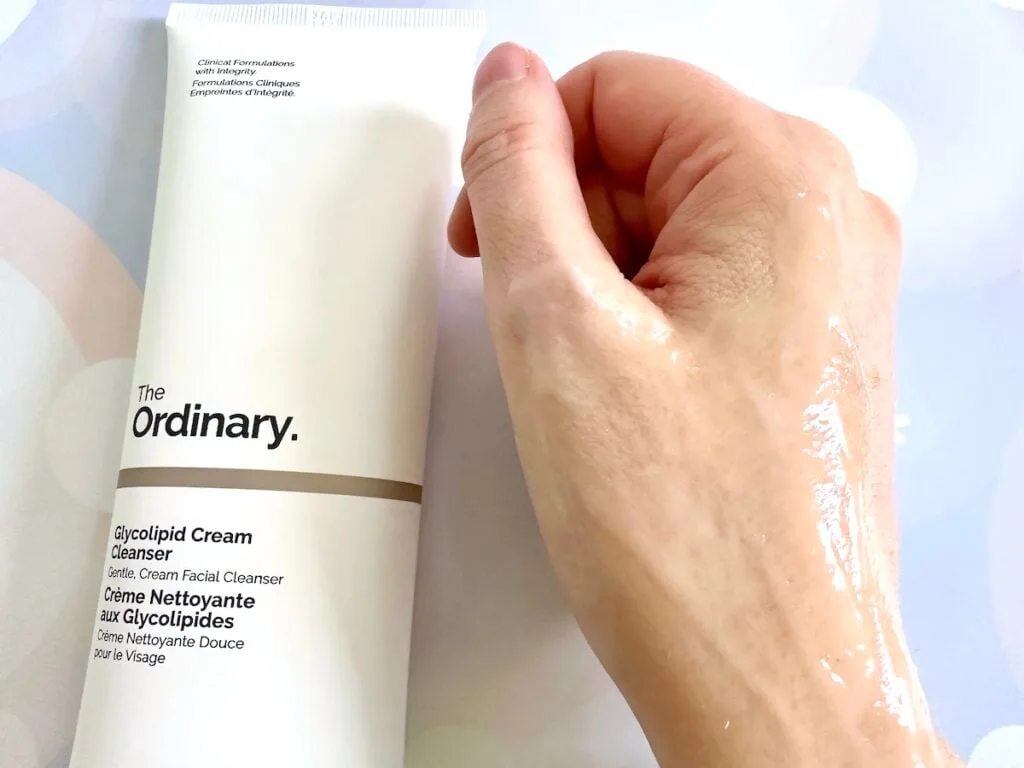 The Ordinary Glycolipid Cream Cleanser flatlay next to sample on hand mixed with water.