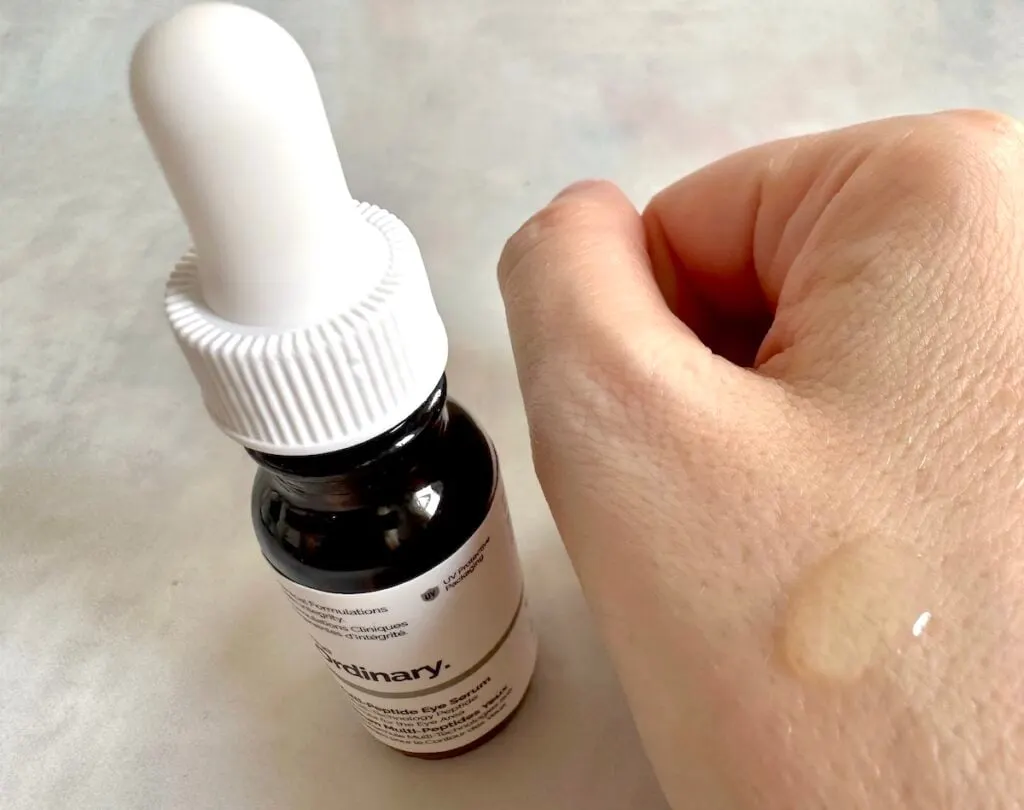 The Ordinary Multi-Peptide Eye Serum bottle next to sample drop on hand.